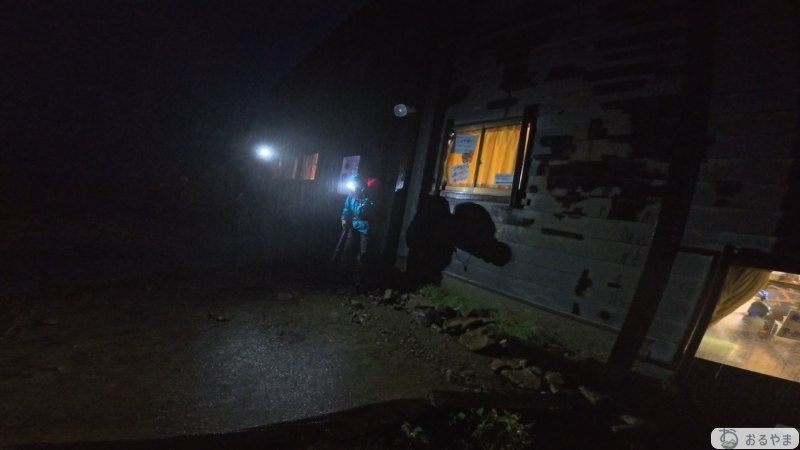 ペツルのヘッドライトを装着して夜の山小屋前で行動するシーン